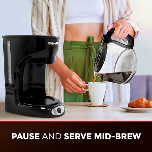 Person pouring coffee from a black coffee maker into a cup.