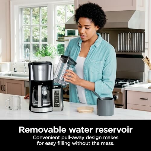 Person using a coffee maker with a removable water reservoir in a kitchen.