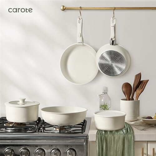 Modern kitchen with cookware set on stove and utensils on counter.